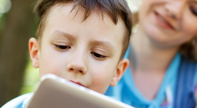 Niño se divierte con su iPad en compañía de su madre